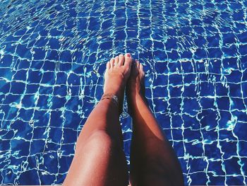 Low section of woman resting on swimming pool