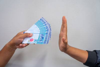 Close-up of hands holding blue over white background