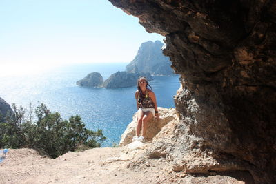 Girl on a cliff in front of the magical island of es vedra in cala d'hort in the ibiza island