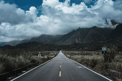 Road leading towards mountains against sky