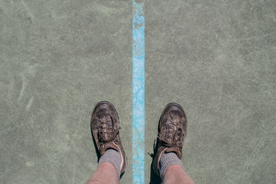 Low section of man wearing shoes standing on street