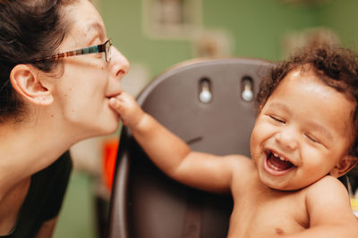 Laughing mother playing with son at home