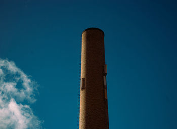 Low angle view of smoke stack against blue sky