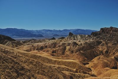 Scenic view of arid landscape against clear blue sky