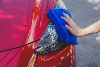 Cropped image of man cleaning red car