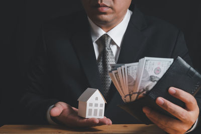 Businessman hold paper house model and check money in wallet