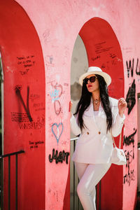 Portrait of young woman standing against wall