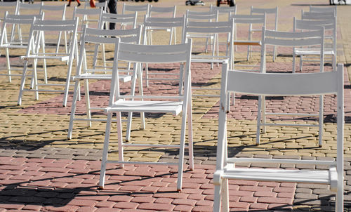 White folding chairs are placed on the square on pavement. quarantine restrictions, mass events