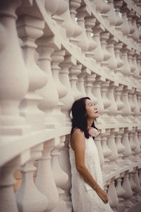 Portrait of young woman standing against wall