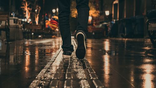 Low section of person standing on wet street during rainy season