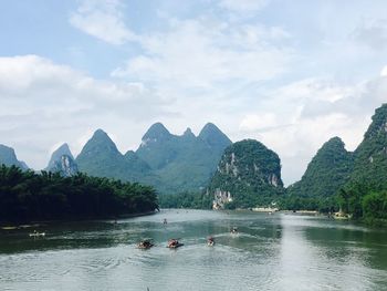 People in boats on river against mountains