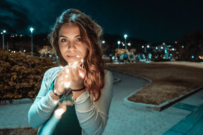 Portrait of smiling young woman in city at night