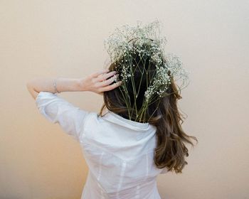 Rear view of woman wearing plants in shirt while standing against wall