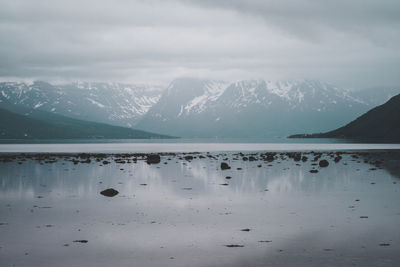 Scenic view of lake by snowcapped mountain against sky