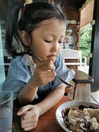 Cute girl holding ice cream on table