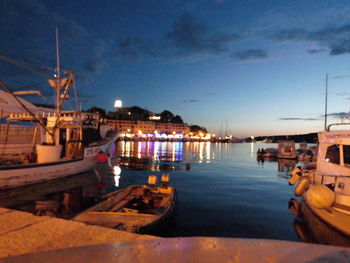 Boats moored at harbor against sky at night