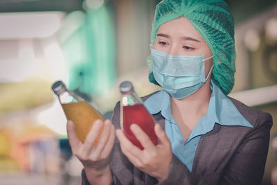 Close-up of woman wearing mask inspecting drinks in factory