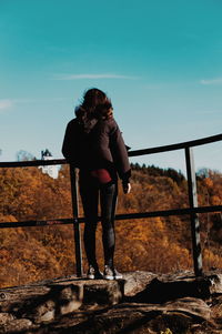 Rear view of woman standing by railing against sky