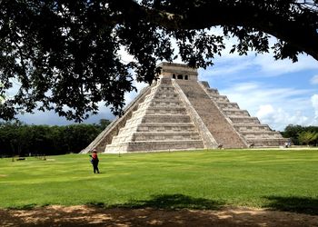 Woman walking on field against old ruin in city