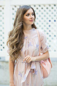 Young woman standing against wall