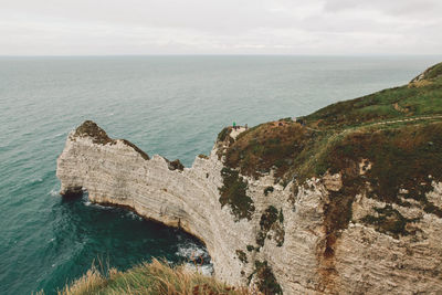 Scenic view of sea by cliff against sky