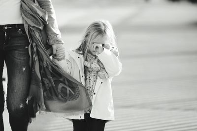 Midsection of mother with daughter walking on road in city