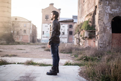 Side view of mid adult man holding barbed wire wrapped baseball bat while standing on land