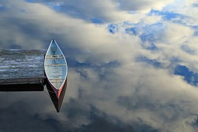 Red canoe with reflected clouds looks like it is floating in the sky