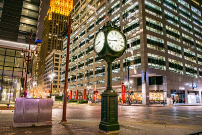 Illuminated street amidst buildings in city at night