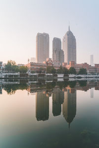 Reflection of buildings in lake against clear sky