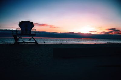 Scenic view of beach against sky at sunset