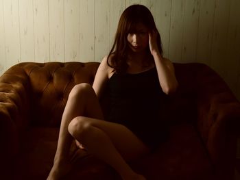 Young woman sitting on sofa at home