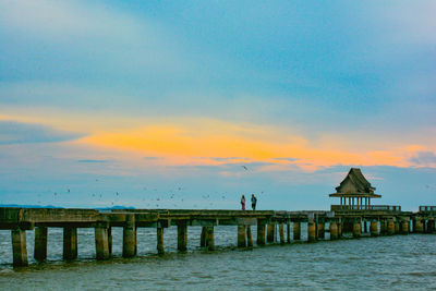 Pier over sea against sky during sunset