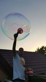 Full length of man standing at bubbles against sky