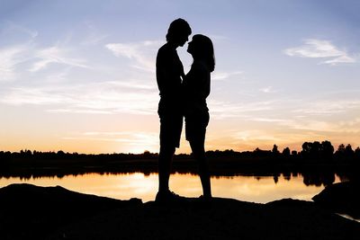 Silhouette couple standing against sky during sunset