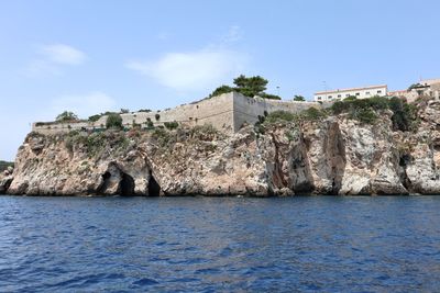 Bridge over sea by buildings against blue sky