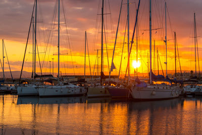 Sailboats moored at harbor during sunset