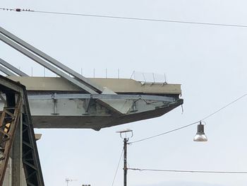 Low angle view of telephone pole against building against clear sky