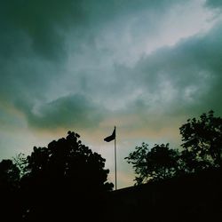 Low angle view of silhouette trees against cloudy sky