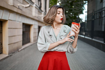 Beautiful young woman standing against red wall