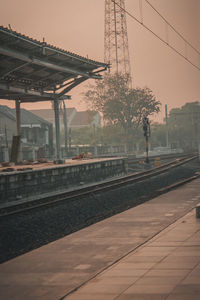 Railroad station platform against sky during sunset