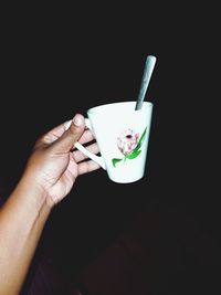 Hand holding coffee cup against black background