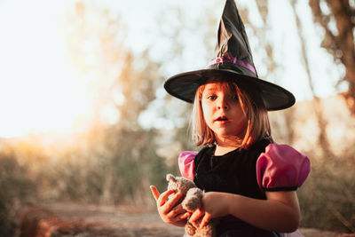 Portrait of girl wearing witchs hat during halloween at forest