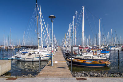 Sailboats moored at harbor against clear blue sky