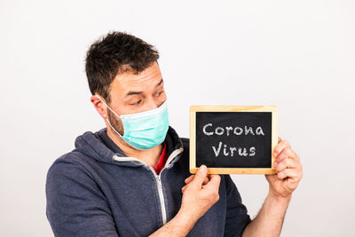 Close-up of man holding blackboard with text against white background