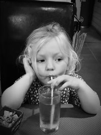 Close-up of cute girl drinking cold water from straw in restaurant