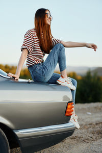 Rear view of woman sitting on car