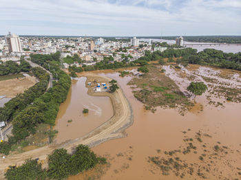 River flooding due to rain causes large mud next to a dam that prevents the rivers from meeting 