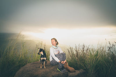 Portrait of woman with dog on beach against sky during sunset