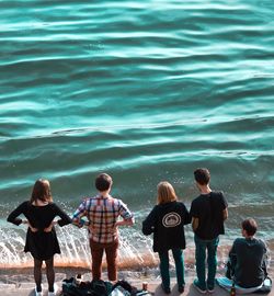 Rear view of friends standing by sea